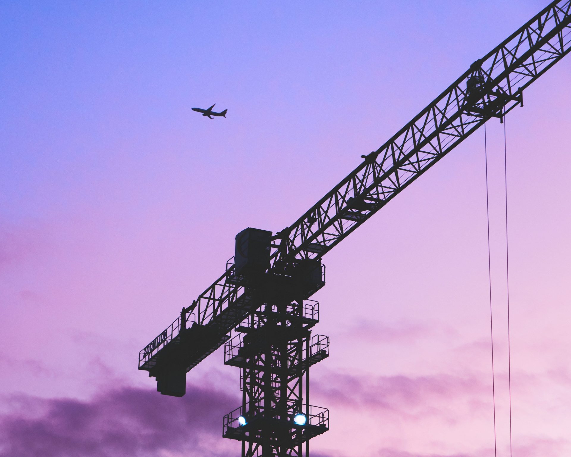 A crane silhouette stands against a vibrant purple sky at dusk, highlighting its structure and the evening atmosphere.