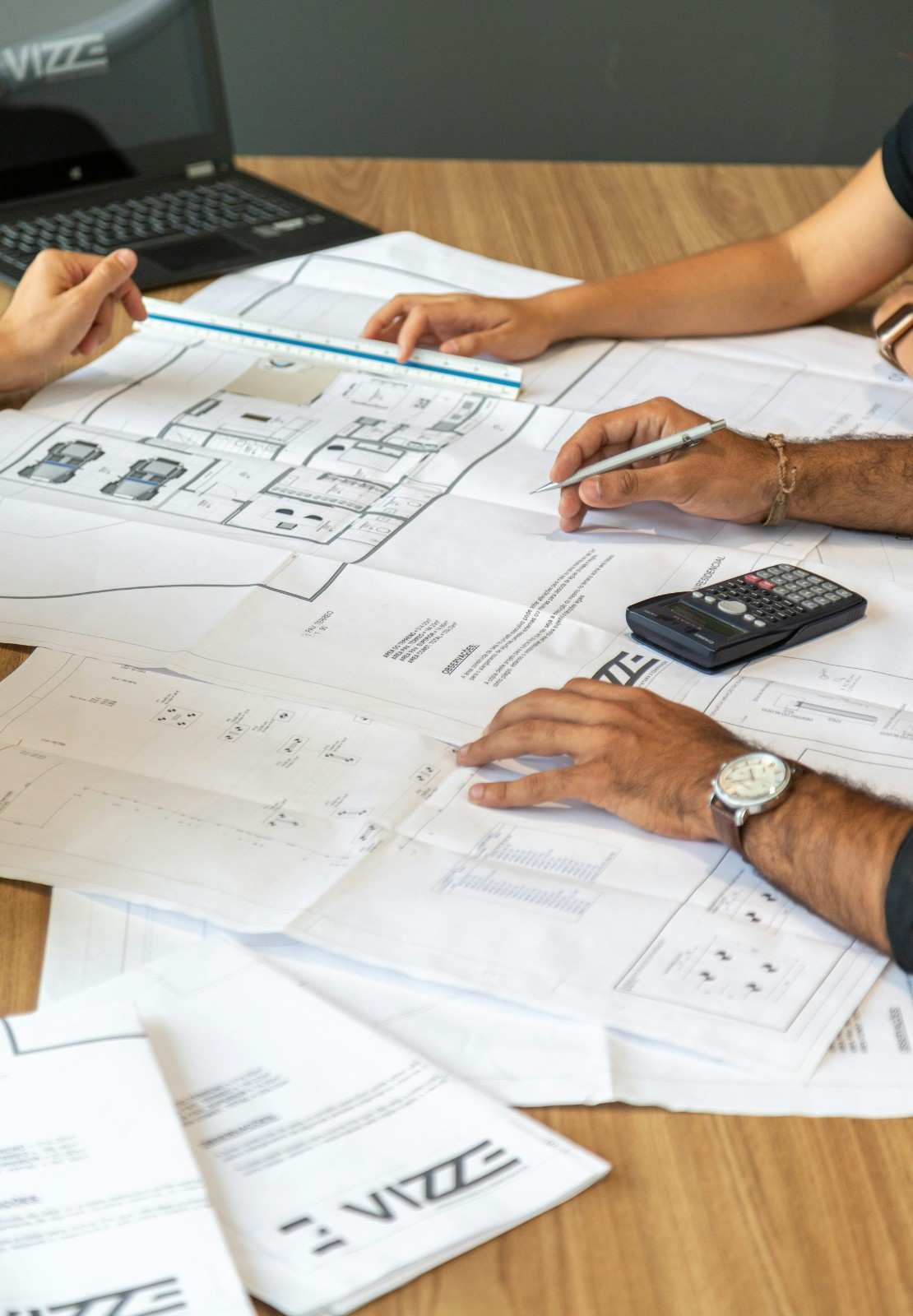 people reviewing architectural blueprints on desk